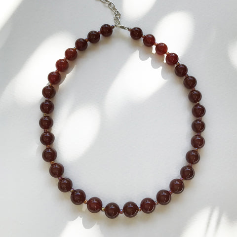 Round dark carnelian stones with glass bead spacers and a sterling silver chain and clasp, 40cm long with sterling silver extension chain and lobster closure.