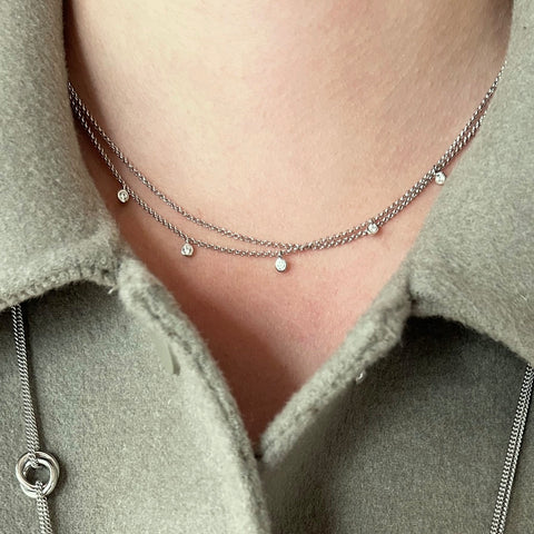 Silver double-chain with 5 small cubic zirconias hanging from one chain. Shown on model.