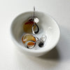 Drop earrings with a cluster of silver 'leaves' and one piece of carnelian. Earrings shown in a small bowl.