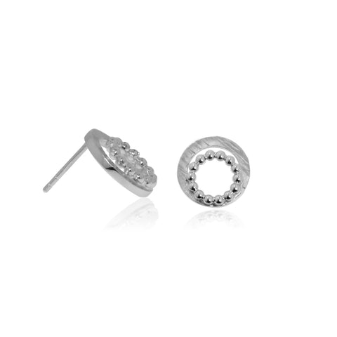 Silver stud earrings made of two rings - one textured, one a ring of beads. Shown on a table. Image shows one on front face, the other side face.