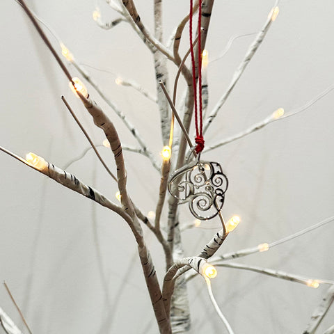 Silver Christmas Ornament wth red cotton cord hanging from a tree