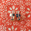 Silver and carnelian drop earrings shown lying flat on printed orange cloth.