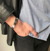 Sterling silver cuff bangle shown on man's wrist with hand in pocket.