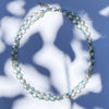 Choker necklace with two twisted strands of freshwater pearls and pale blue glass beads. Shown on mottled blue background.