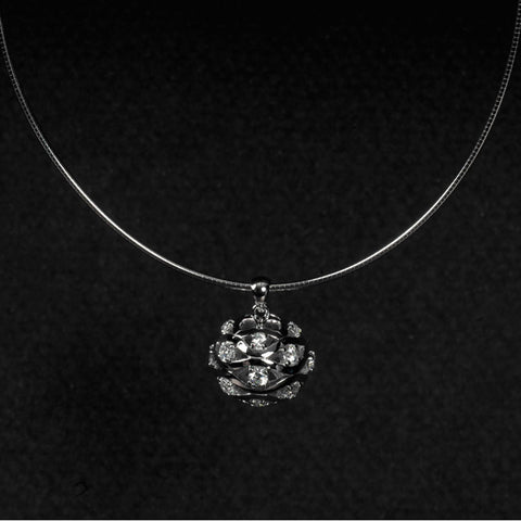 Silver ball-shaped pendant with cut-out wave patterns and studded with white cubic zirconia stones. Shown hung on a silver choker