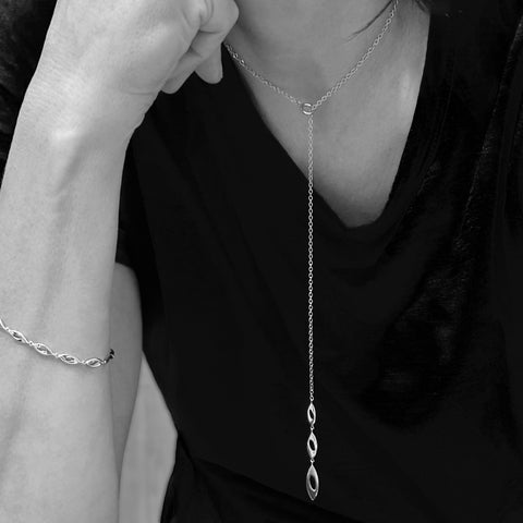 Y-shaped silver necklace with w open links shown on model with matching bracelet.
